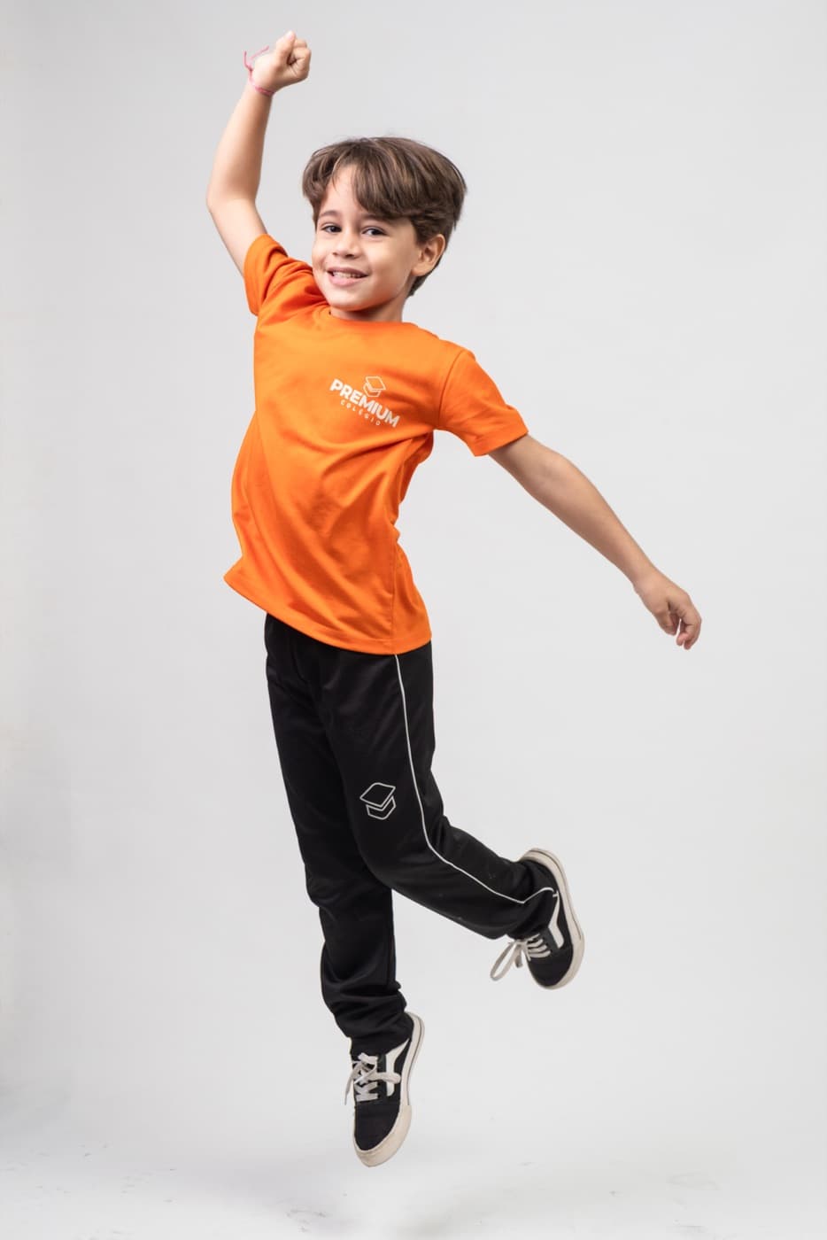 Criança do Fundamental I saltando com o uniforme laranja do PREMIUM