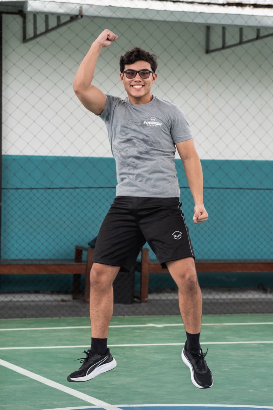Aluno comemorando com o punho erguido na quadra do colégio
